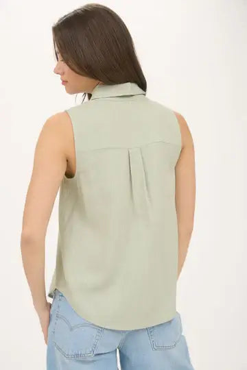Mujer vista de espaldas con blusa sin mangas verde y canesú trasero, estilo casual chic.
